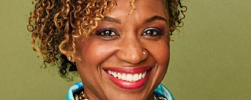 Headshot of women in brightly colored shirt on a pea green background.