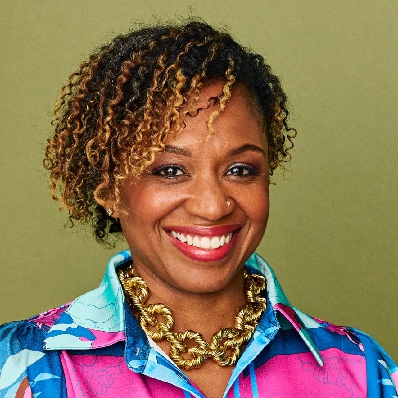 Headshot of women in brightly colored shirt on a pea green background.