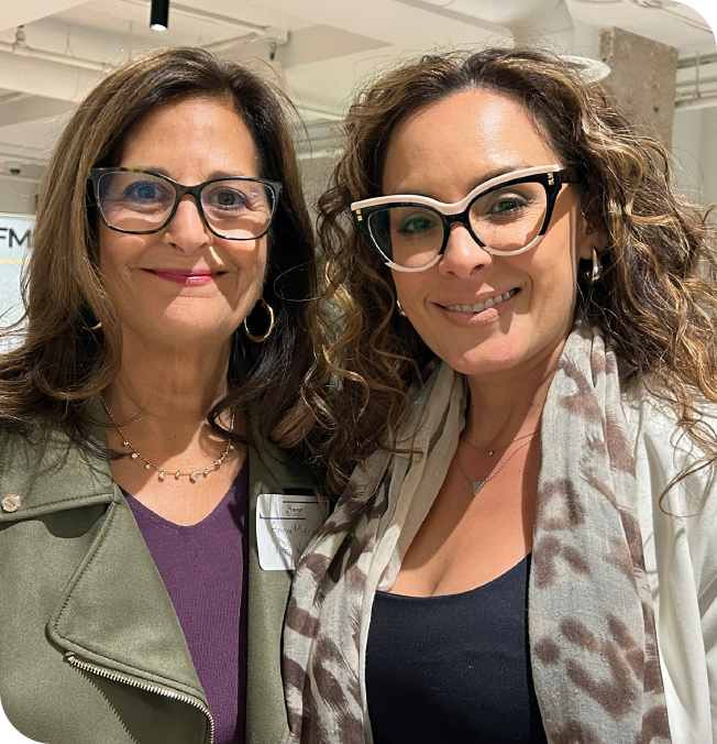 Two WHIP members smiling together at a membership event, wearing glasses and name tags.